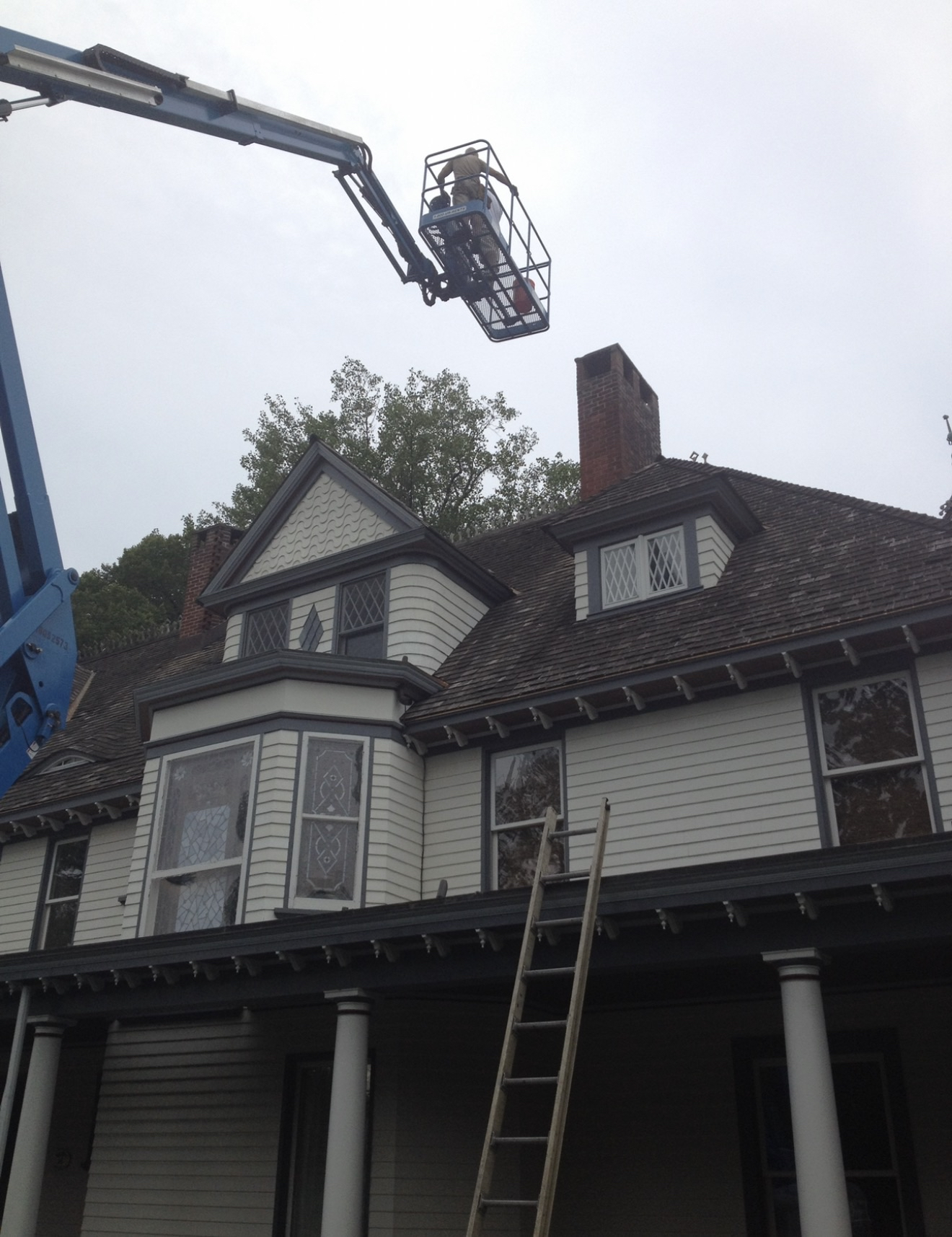 Electrician working from a bucket lift on exterior service of a Victorian home
